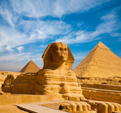 Full profile of Great Sphinx including pyramids of Menkaure and Khafre in the background on a clear sunny, blue sky day in Giza, Cairo, Egypt with no people