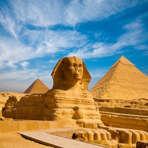 Full profile of Great Sphinx including pyramids of Menkaure and Khafre in the background on a clear sunny, blue sky day in Giza, Cairo, Egypt with no people
